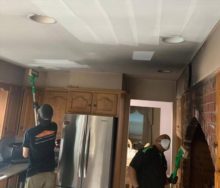 SERVPRO technicians with tools in a soot-covered kitchen