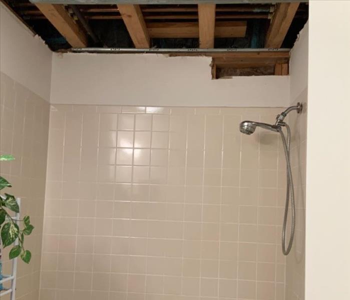 Bathroom ceiling with a portion of the drywall removed exposing interior framework