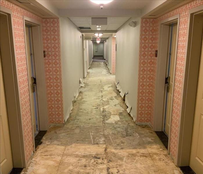 Commercial building hallway with subfloor exposed and damaged walls