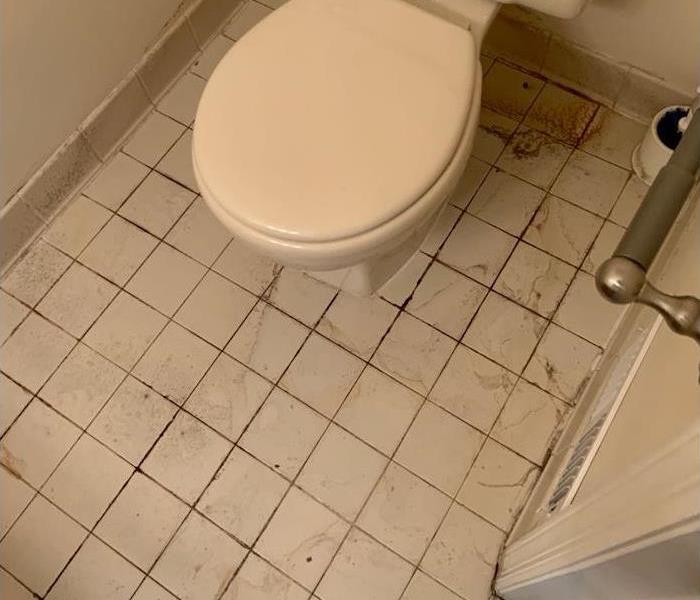 Toilet on tile floor with debris