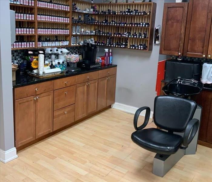 A salon washing station with stained, water-damaged drop ceiling tiles and wet flooring