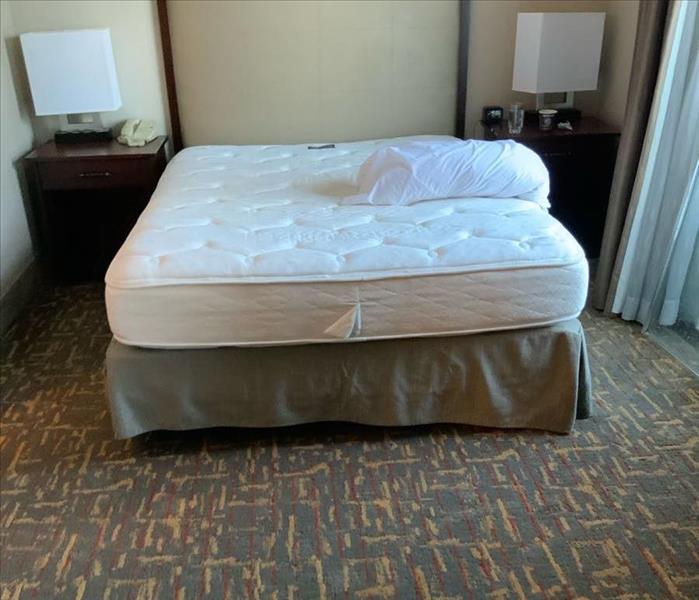 Bed with bare mattress in a room with nightstands