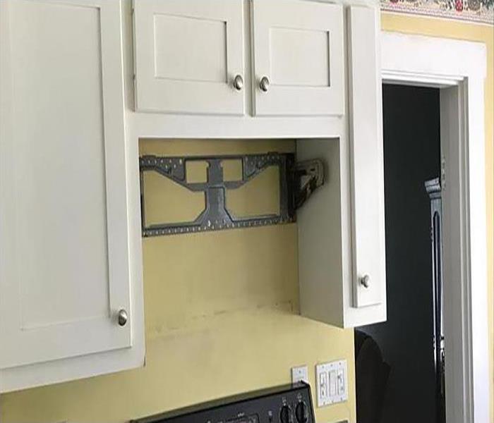 Kitchen cabinets above a stove on a yellow wall. 