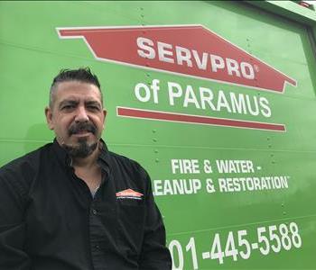 A man with a black shirt on standing in front of a SERVPRO vehicle.