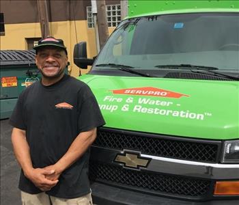 A man with a beanie on standing in in front of a SERVPRO vehicle.