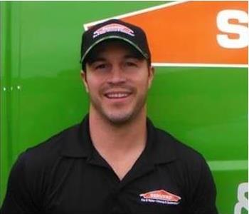 A male employee standing in front of a SERVPRO truck. 