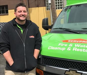 An employee standing next to a SERVPRO van. 