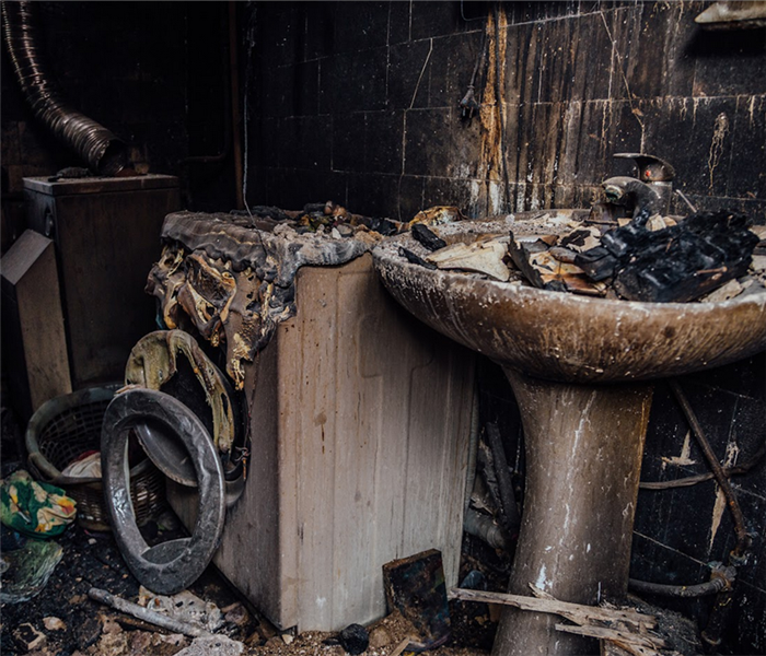 a fire damaged bathroom with debris and soot everywhere