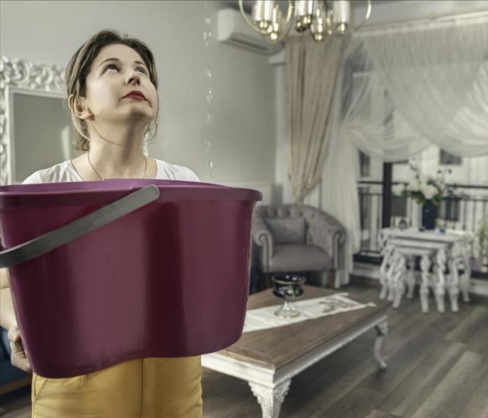 woman holding a bucket catching leaking water.