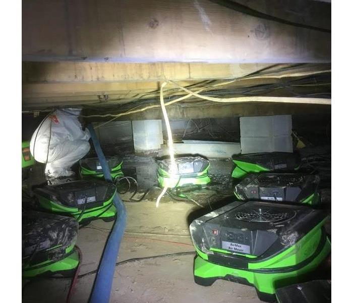 a SERVPRO worker and SERVPRO equipment in the crawlspace of a house