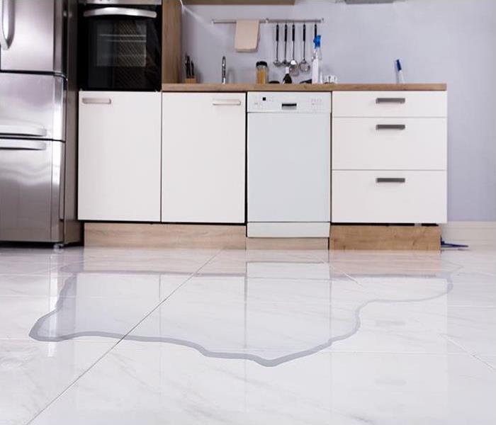 A kitchen floor with water on white floors. 